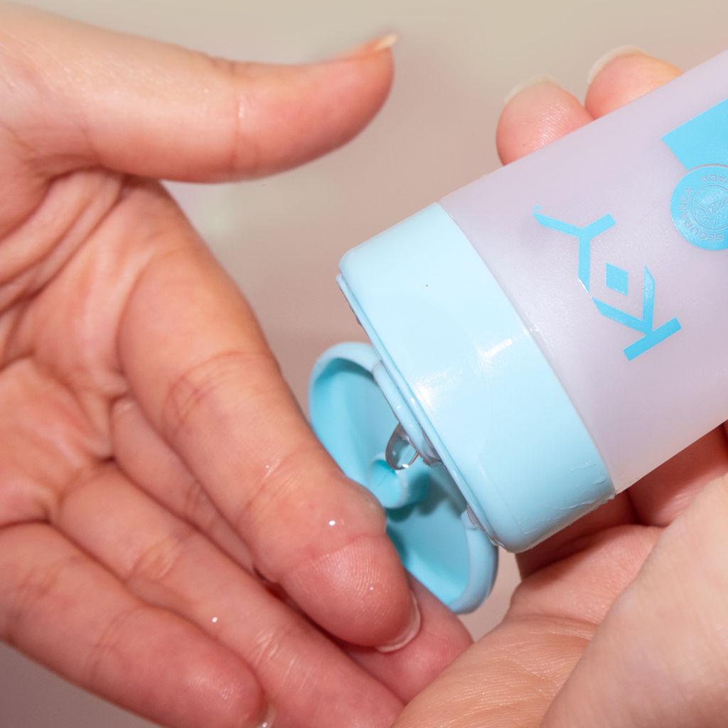 Mãos aplicando gel íntimo KY, relacionado a corrimento vaginal.